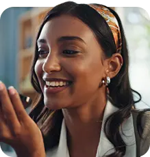 Mulher sorridente usando tiara estampada, interagindo com smartphone para atendimento digital.